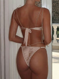 Back view of a woman in a beige satin bikini with adjustable tie straps