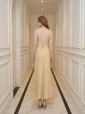 Back view of a woman in a yellow jacquard floral midi dress with a round neckline and criss-cross back straps.