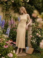 Woman posing in a garden wearing a sleeveless yellow jacquard floral midi dress with a round neckline.