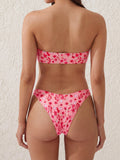 Woman wearing a pink floral print strapless bikini set with a gold embellishment on the front of the top, back view.