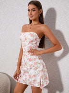 Woman in a white strapless mini dress with a pink floral print, looking to the side.