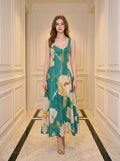 Woman wearing a green midi dress with a large floral print, standing in a hallway.