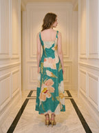 Back view of a woman in a green midi dress with a floral print, standing in a hallway.