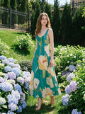 Woman wearing a green midi dress with a floral print, standing in a garden with hydrangeas.
