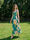 Woman wearing a green midi dress with a floral print, walking in a grassy outdoor setting.