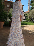 Back view of a woman in a white sheer maxi cover-up with a tiered hem and nautical print