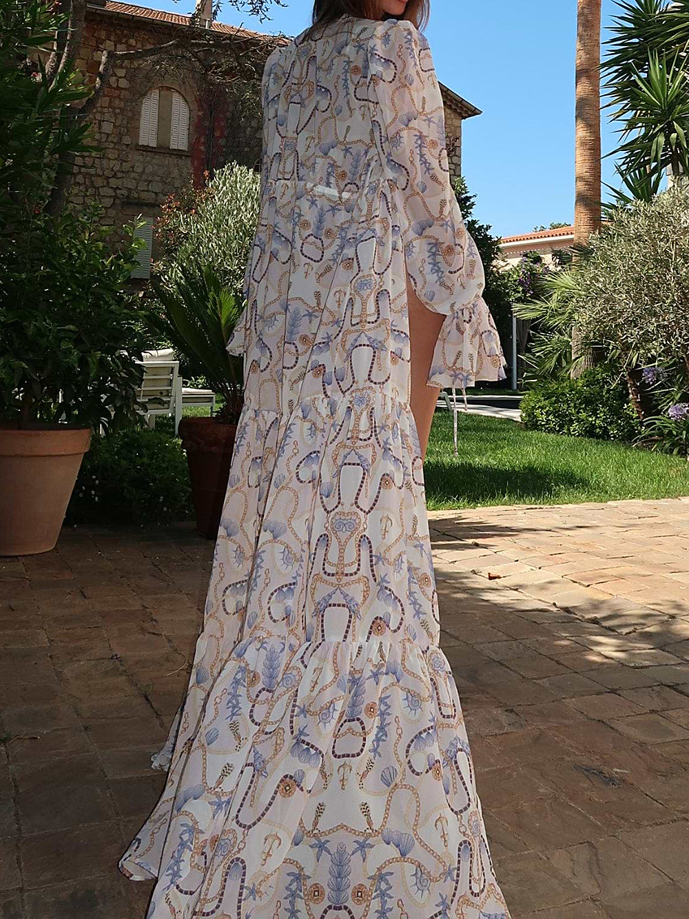 Back view of a woman in a white sheer maxi cover-up with a tiered hem and nautical print