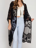 Woman wearing a black lace duster over a white top and light blue jeans
