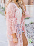 Woman wearing a pink lace duster over a white top and denim shorts