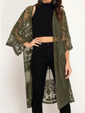 Woman wearing an olive green lace duster over a black crop top and black jeans