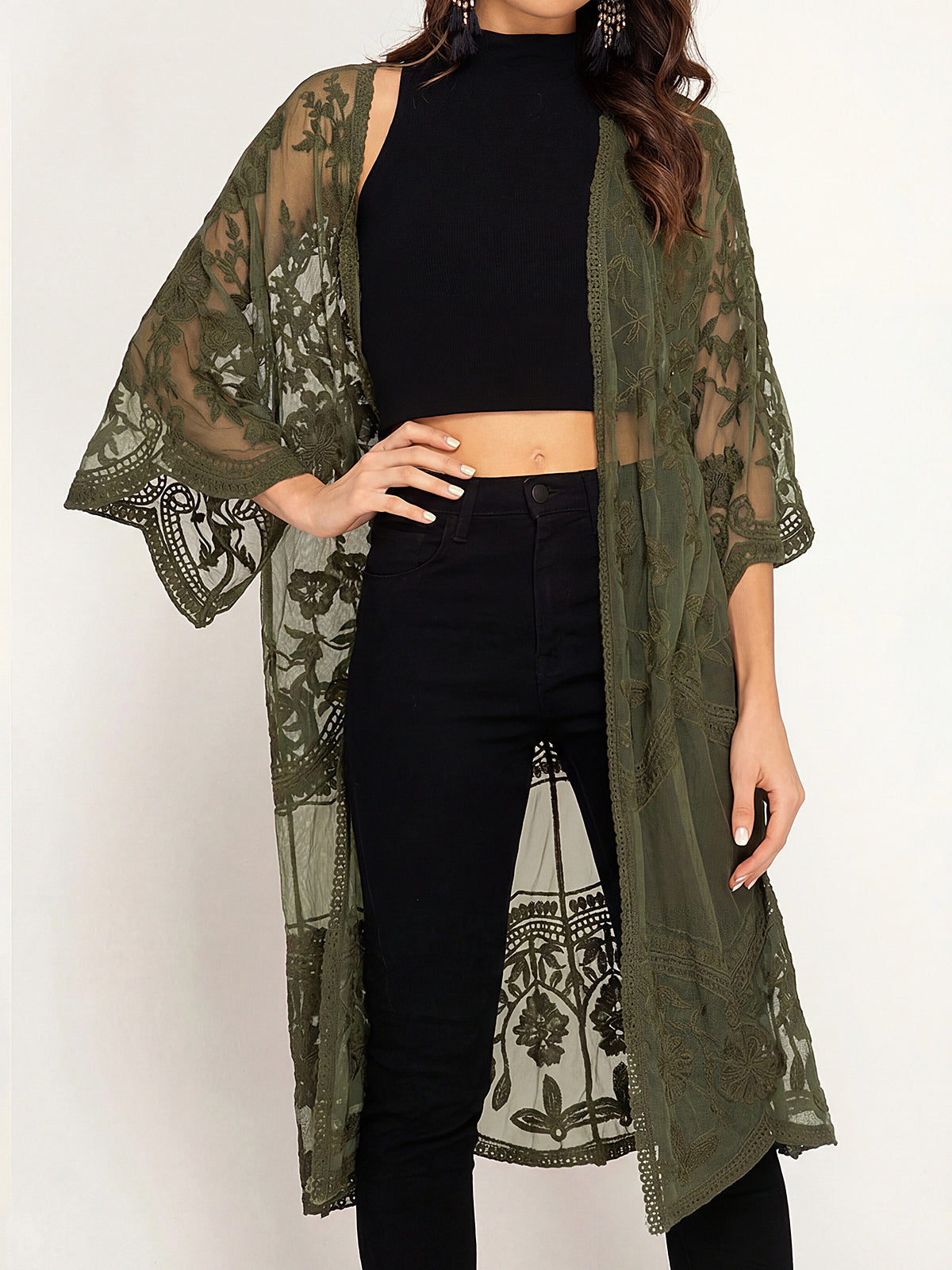 Woman wearing an olive green lace duster over a black crop top and black jeans