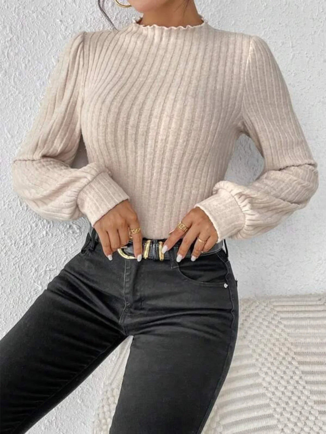 Woman wearing a cream ribbed knit bodysuit with puff sleeves and a mock neck