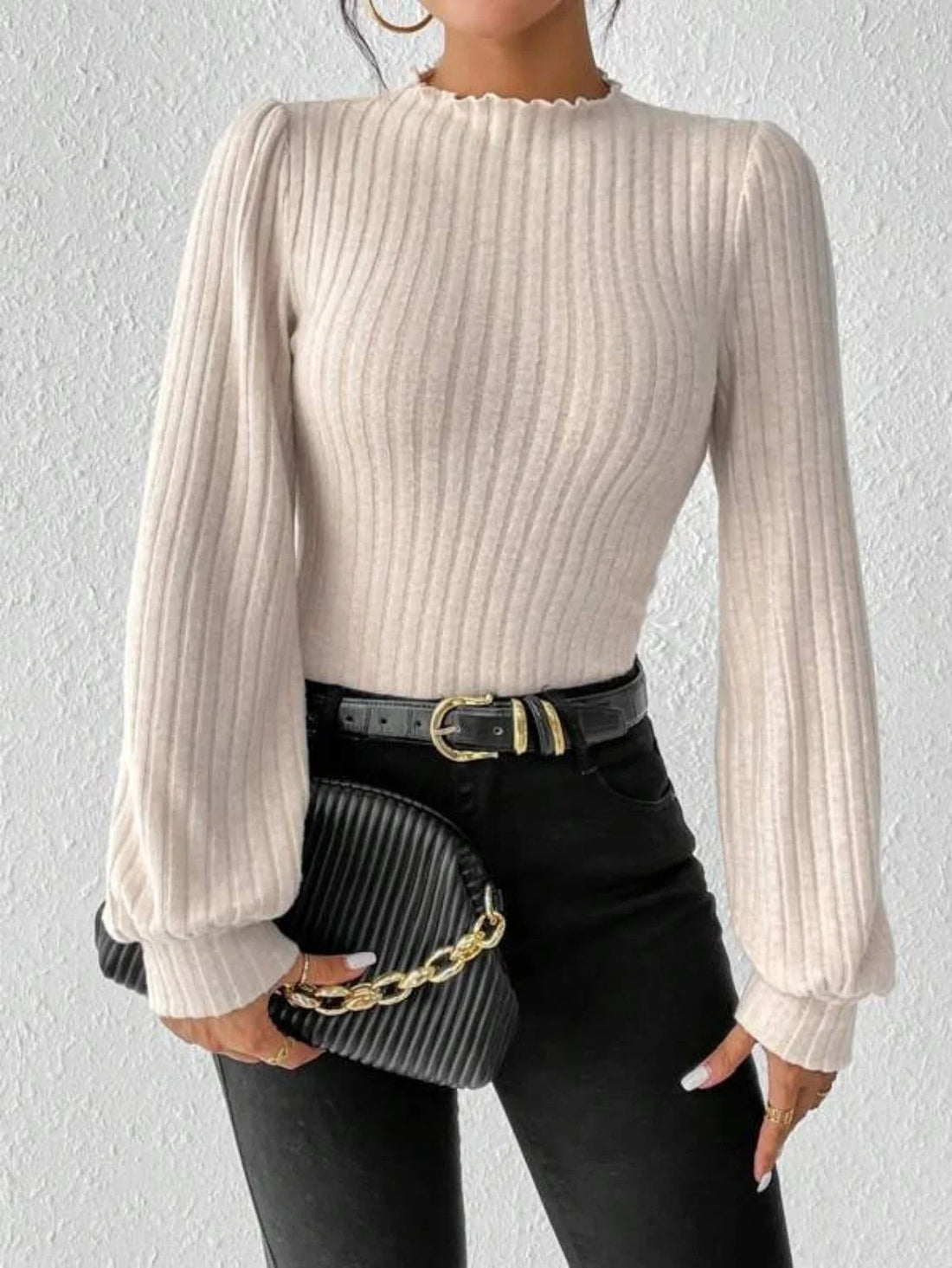 Woman wearing a cream ribbed knit bodysuit with puff sleeves and a mock neck