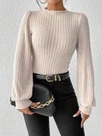 Back view of a woman in a cream ribbed knit bodysuit with long puff sleeves