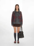 Woman wearing a grey and red plaid collared knit jacket with a brown skirt and grey knee-high socks.