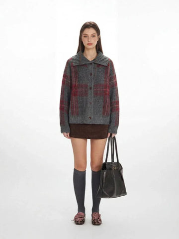 Woman wearing a grey and red plaid collared knit jacket with a brown skirt and grey knee-high socks.