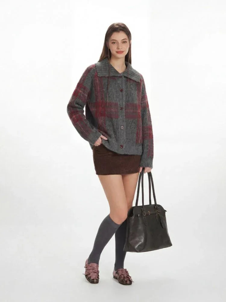 Front view of a woman in a plaid collared knit jacket, posing with hands in pockets.