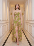 Woman wearing a green floral print strapless maxi dress with a high slit