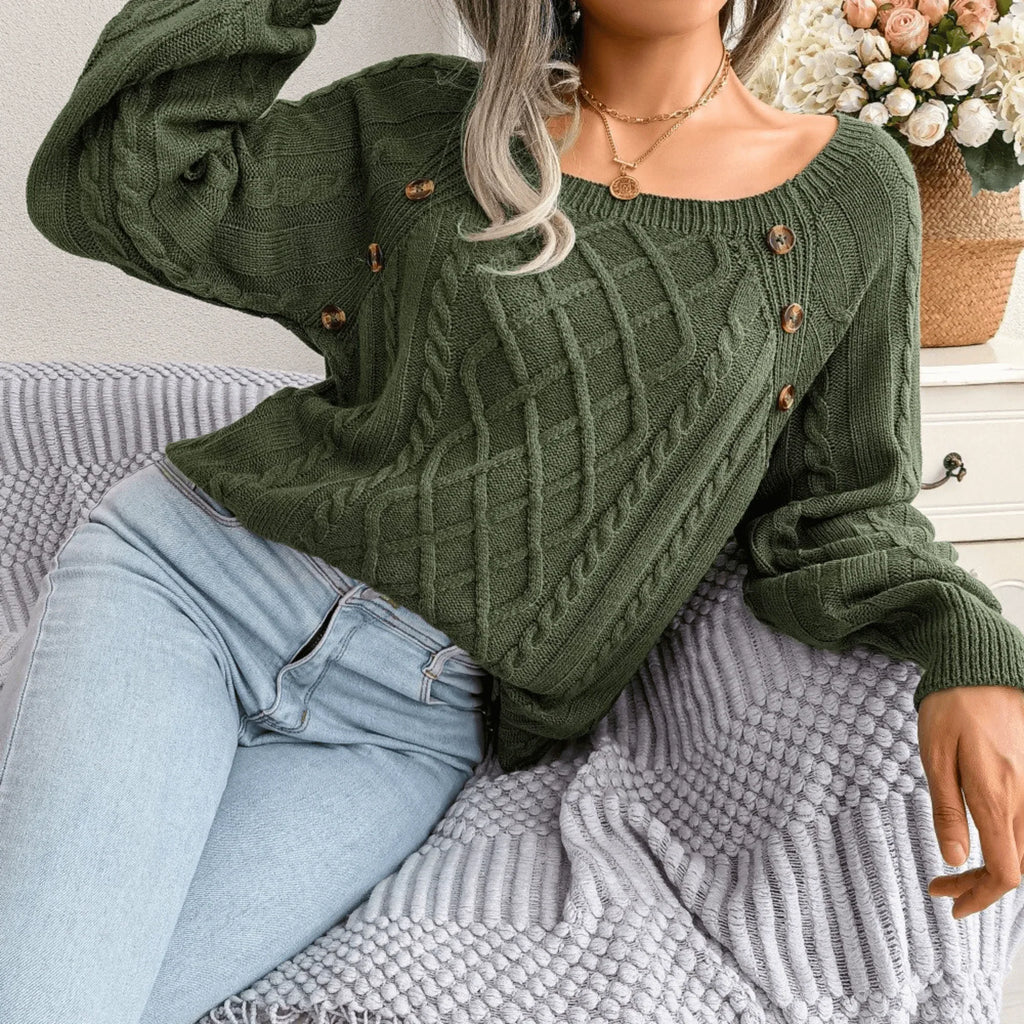 Woman sitting on a couch wearing a green cable knit sweater and light wash jeans