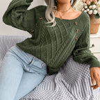 Woman sitting on a couch wearing a green cable knit sweater and light wash jeans