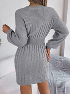 Back view of a woman wearing a grey cable knit mini dress with a ribbed waistband.