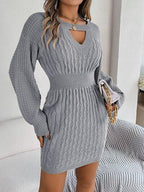 Woman carrying a white clutch with a gold chain, wearing a grey cable knit mini dress.