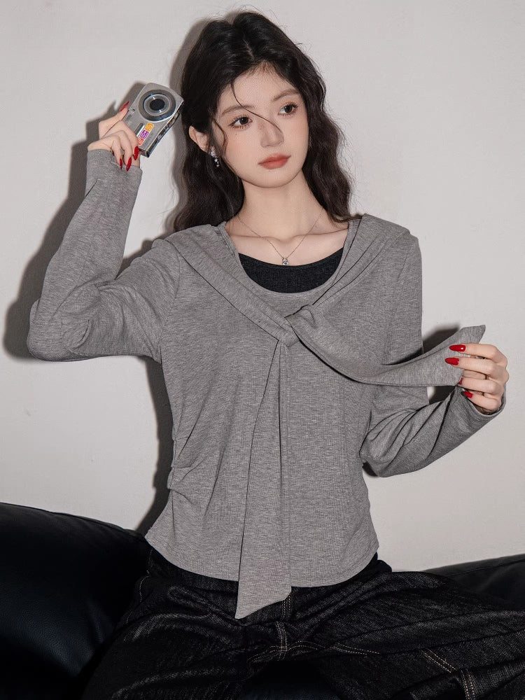 Close-up of a woman in a grey long-sleeve top showcasing the draped neckline detail.