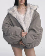 Woman wearing a grey bomber jacket with white faux fur lining and hood