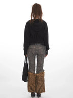 Back view of a woman in a black cropped hooded zip-up jacket and patterned pants.