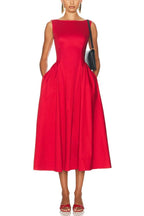 Woman wearing a sleeveless red midi dress with pockets and a boat neckline.
