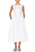 Woman wearing a sleeveless white midi dress with pockets and a boat neckline.