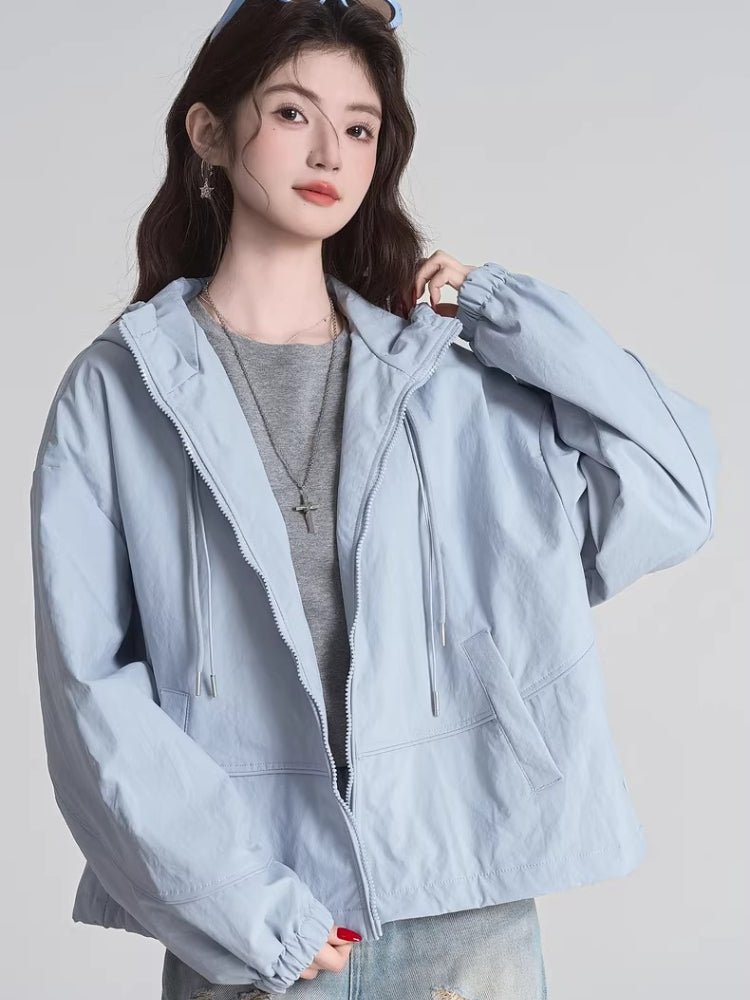 Woman wearing a light blue hooded jacket with a full zip closure and drawstring details.