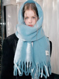 Close-up of a woman's face with a light blue mohair blend scarf wrapped around her head and neck.