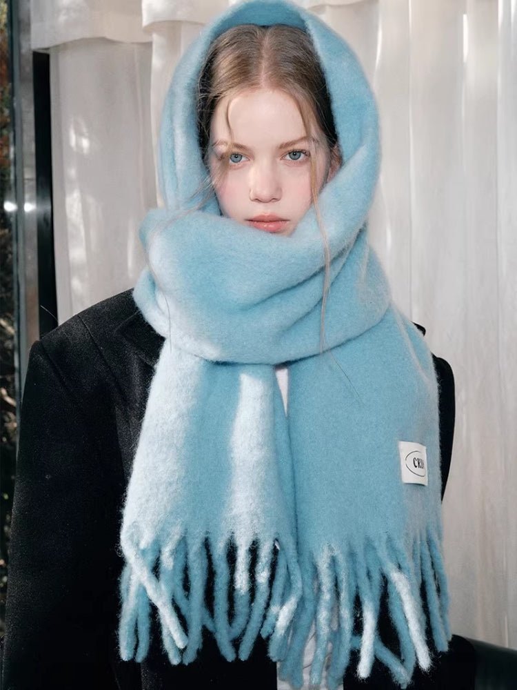 Close-up of a woman's face with a light blue mohair blend scarf wrapped around her head and neck.