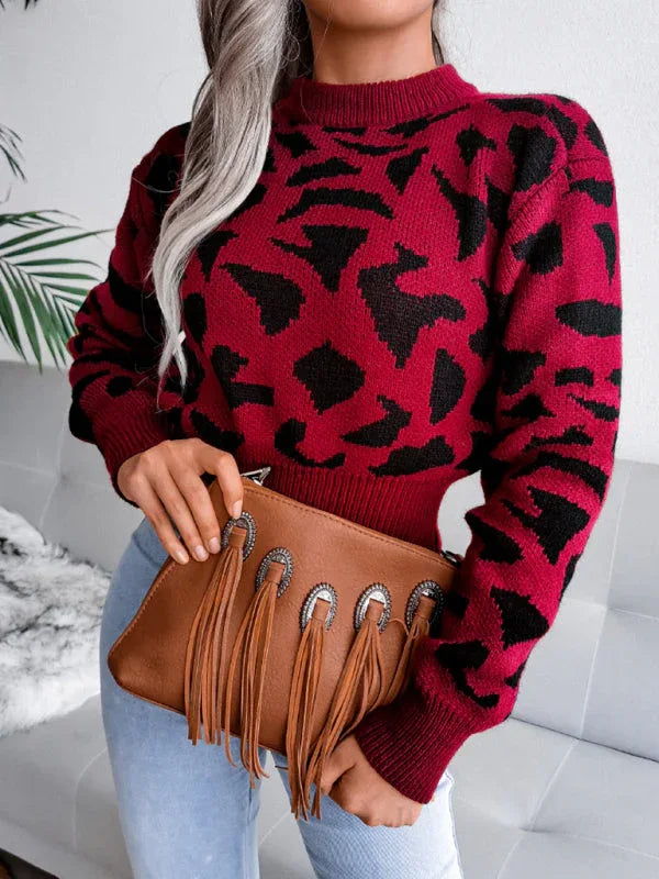 Woman holding a brown fringed clutch while wearing a red and black leopard print sweater.