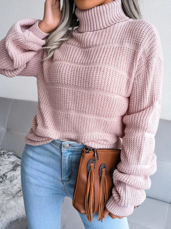 Woman wearing a pink knit turtleneck sweater with bishop sleeves and light wash denim jeans. Main image