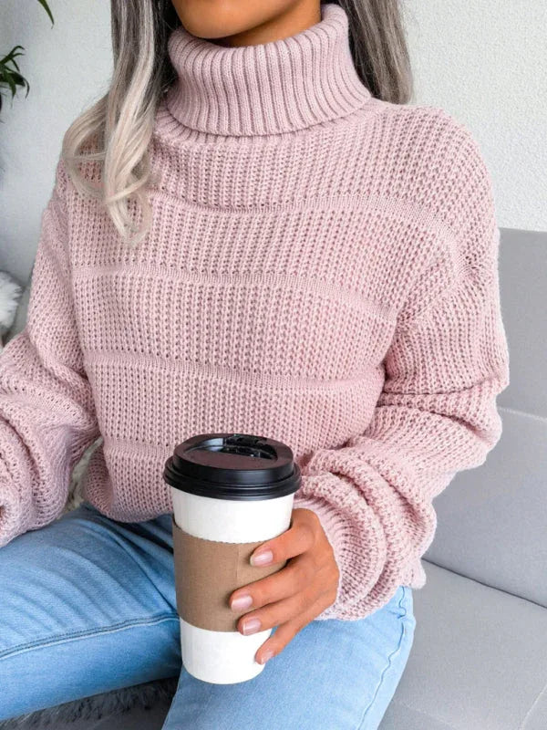 Woman holding a coffee cup while wearing a pink knit turtleneck sweater