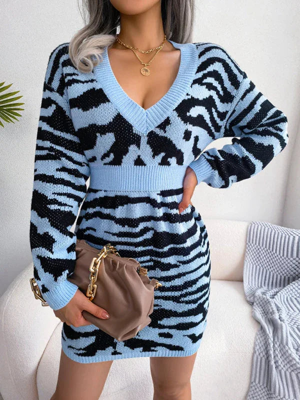 woman wearing a blue and black tiger print knit dress with a v-neck and long sleeves, holding a handbag