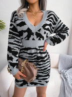 woman wearing a grey and black tiger print knit dress with a v-neck and long sleeves, holding a handbag