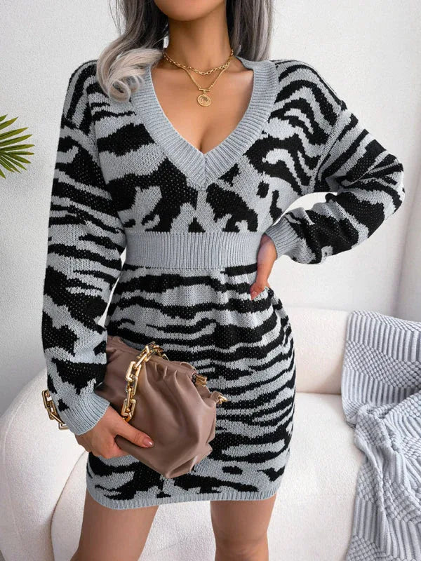 woman wearing a grey and black tiger print knit dress with a v-neck and long sleeves, holding a handbag