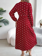 Back view of a woman in a red polka dot midi dress with a pleated skirt