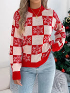 Front view of a woman wearing a red and white checkered knit sweater with snowflake print and a gold necklace