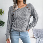 Woman wearing a grey cable knit sweater with decorative buttons and light wash denim jeans