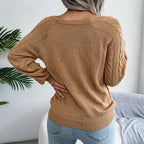 Back view of a woman wearing a tan cable knit sweater with a square neckline and decorative buttons.