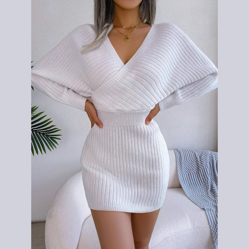 Woman wearing a white ribbed knit mini dress with batwing sleeves and a deep V-neck
