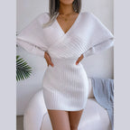 Woman wearing a white ribbed knit mini dress with batwing sleeves and a deep V-neck
