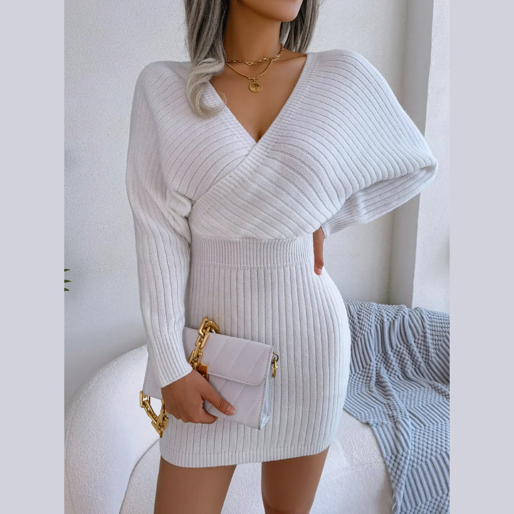Woman holding a white clutch bag while wearing a white ribbed knit mini dress