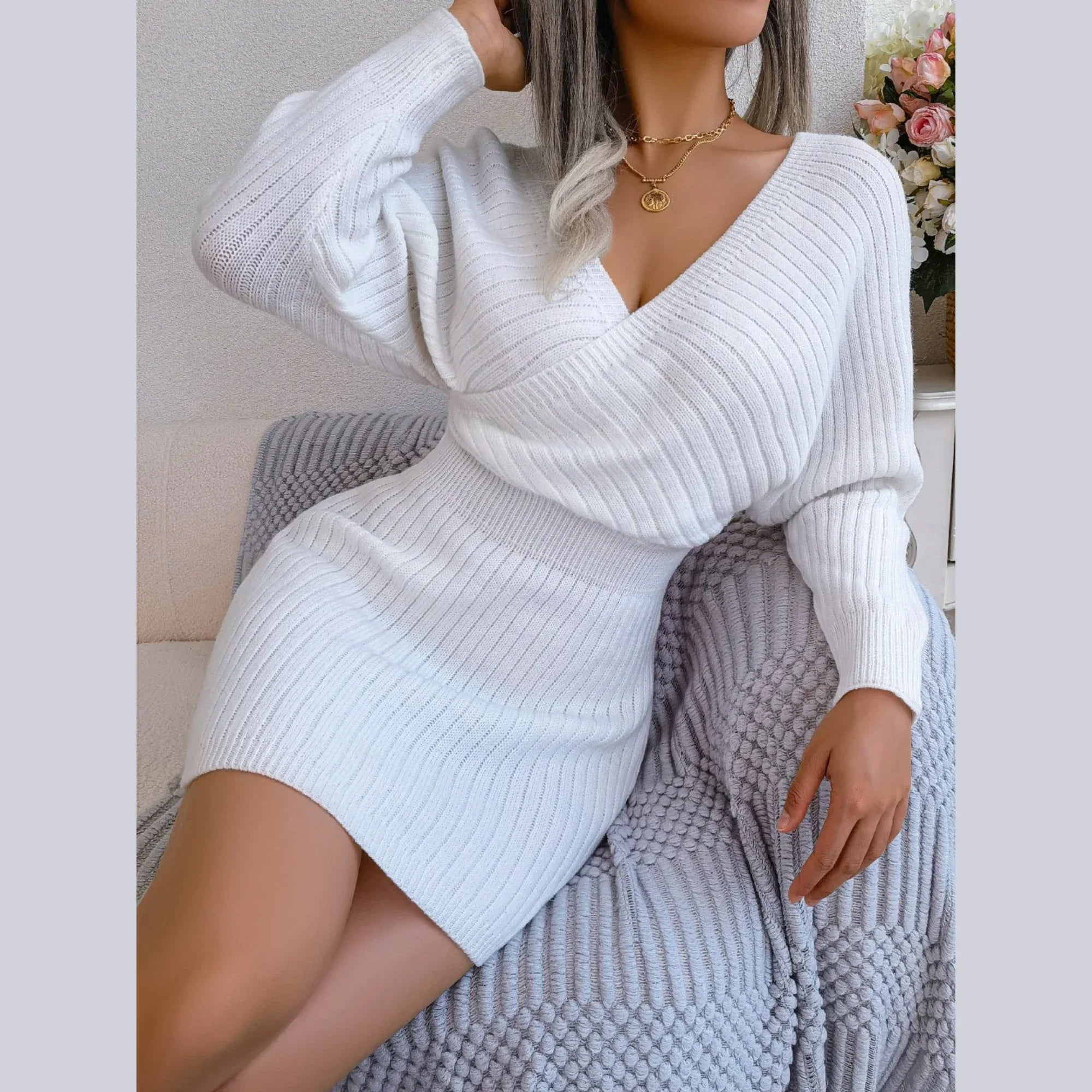 Woman posing in a white ribbed knit mini dress with batwing sleeves