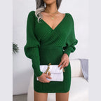 Green knit wrap mini dress with V-neck and bishop sleeves, held with a white clutch
