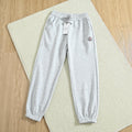 Light gray Moncler jogger pants laid flat on a cream rug.